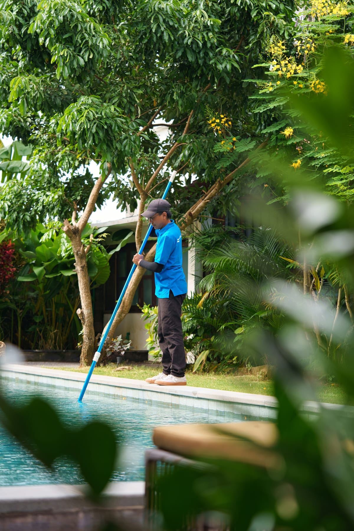 Brushing and vacuuming a villa pool during a maintenance visit in Bali