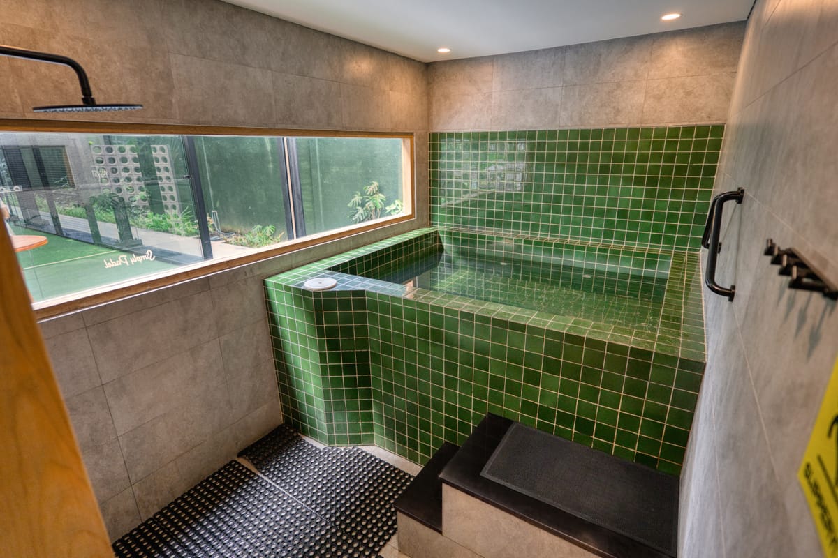 Green-tiled cold plunge pool with a rain shower and stone-clad walls, built by Tropical Pool at a wellness club in Bali