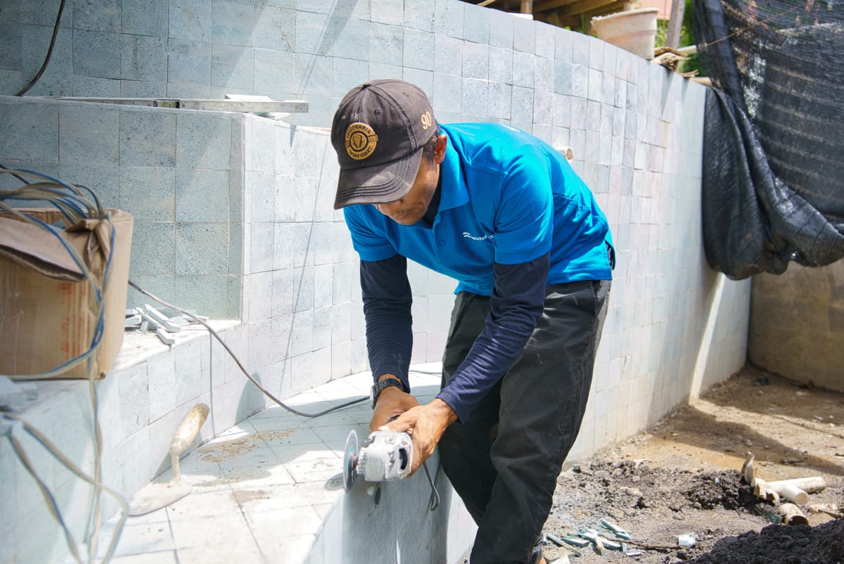 A Tropical Pool tradesman working on a tiled pool shell during construction in Bali