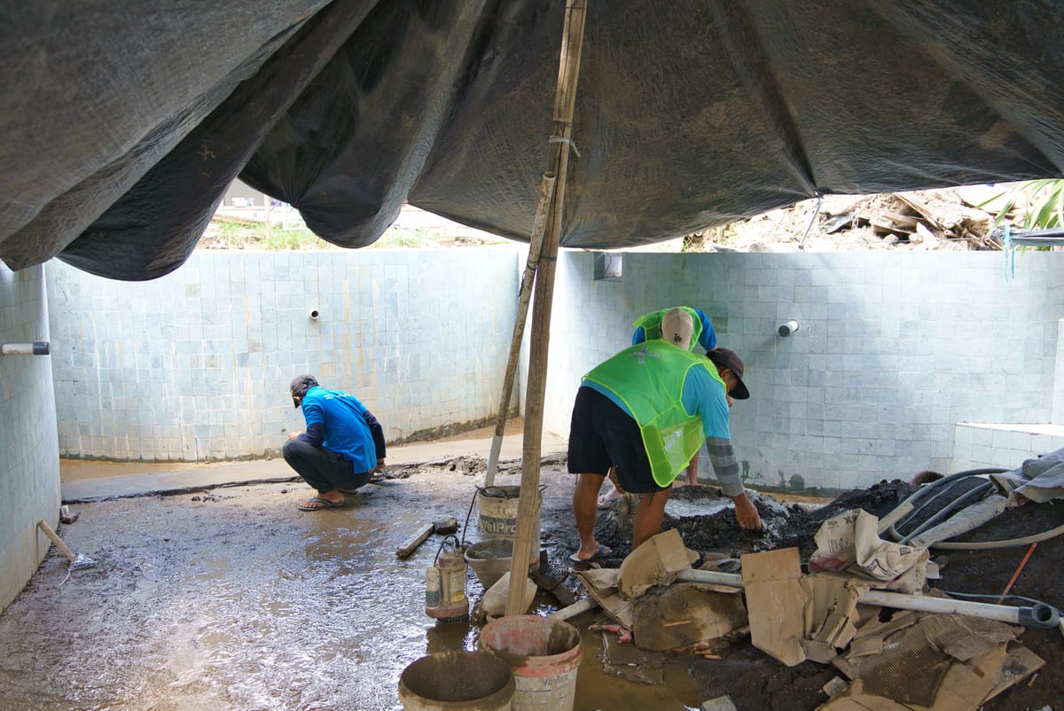 Tropical Pool crew finishing the floor screed inside a tiled pool shell during construction in Bali