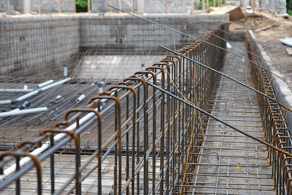 Close-up of the steel reinforcement cage along a pool wall before concrete, on a Tropical Pool build
