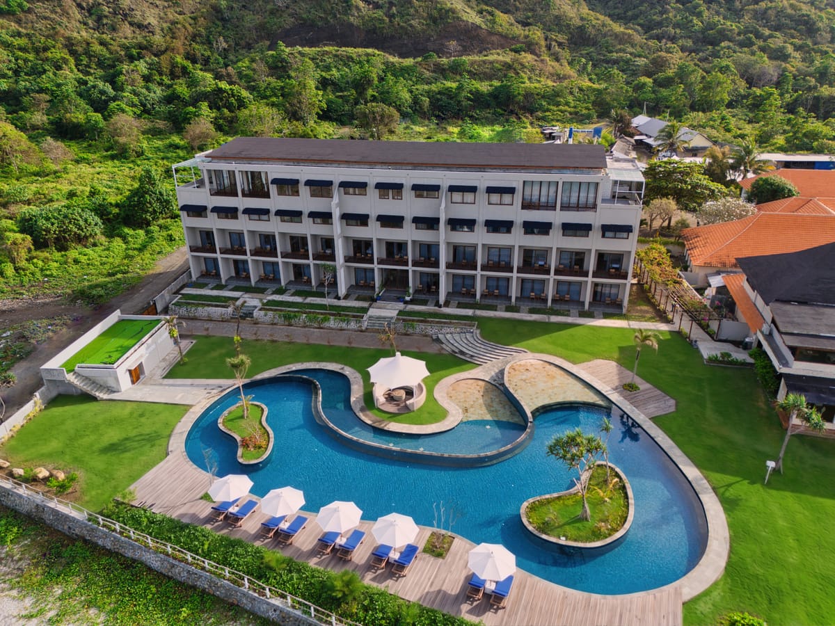 Aerial view of a beachfront resort and its freeform pool on a private bay in Sumbawa