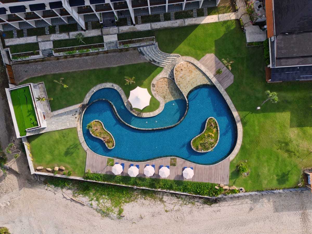 Top-down aerial of a freeform resort pool beside the beach in Sumbawa