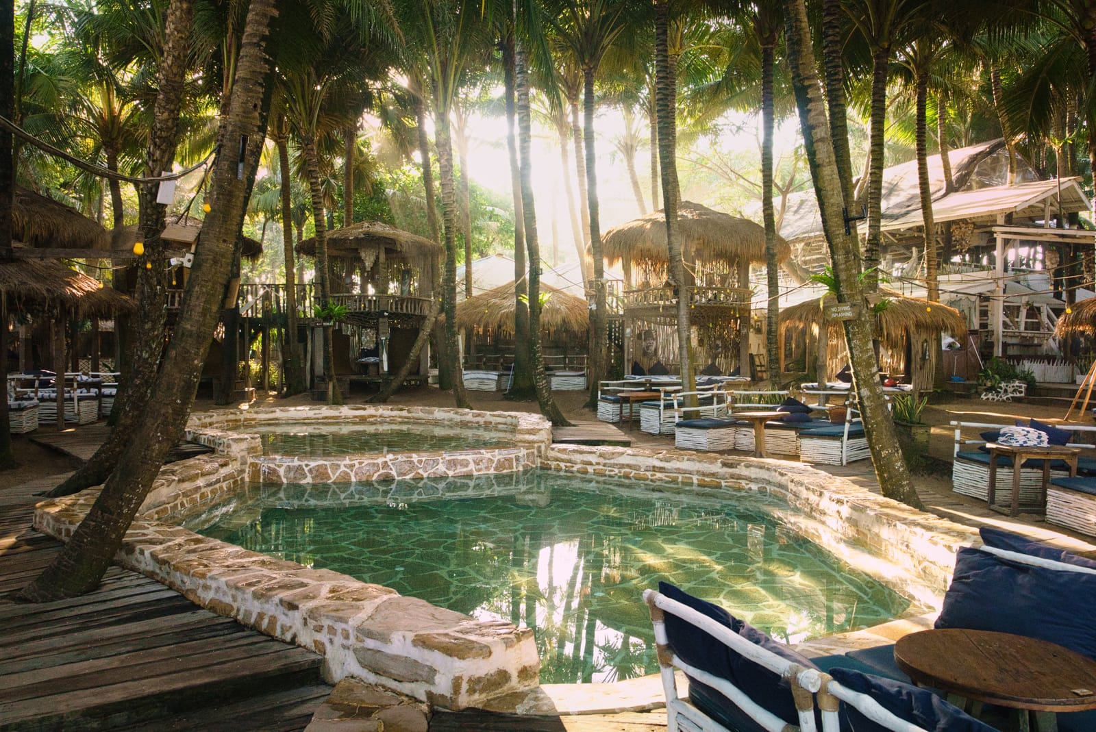 Natural-stone beach club pools under tall palms at golden hour at La Brisa, Canggu, Bali