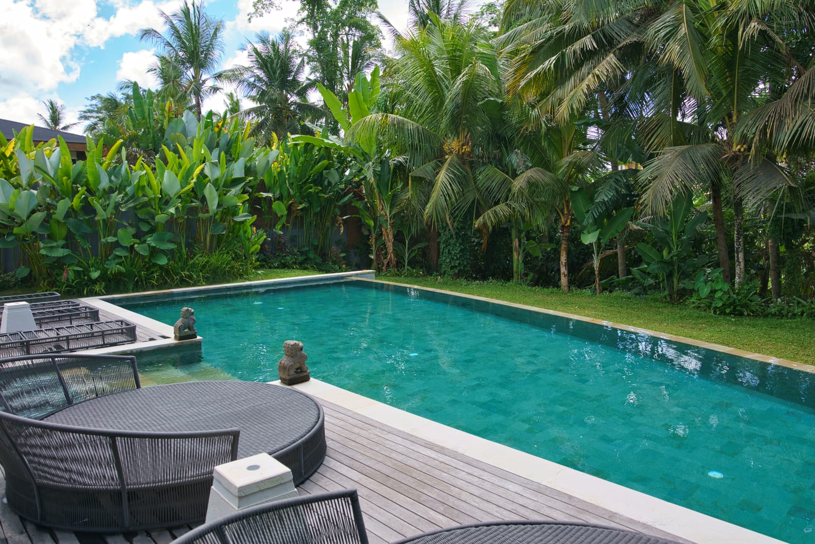Emerald villa pool with sun loungers framed by tropical garden