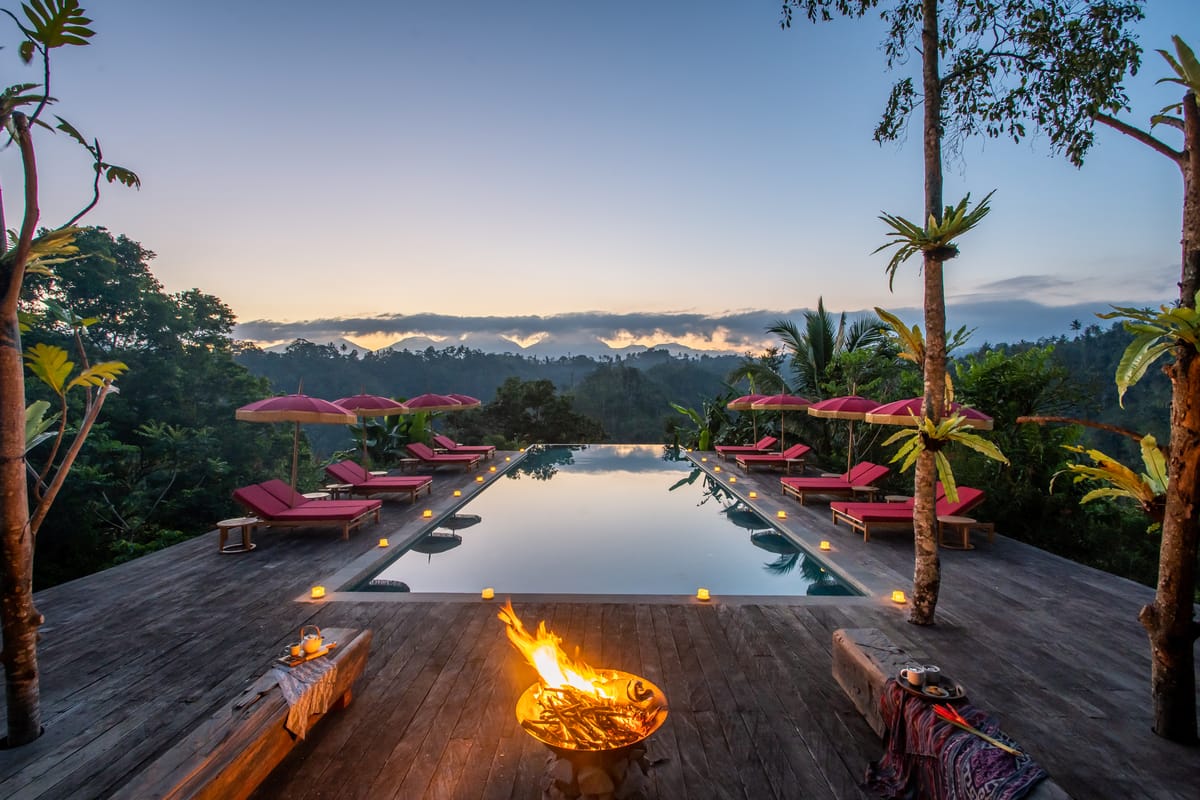 Infinity pool at dusk with a fire bowl and candlelight overlooking the mountains at a Michelin Key resort in Bali