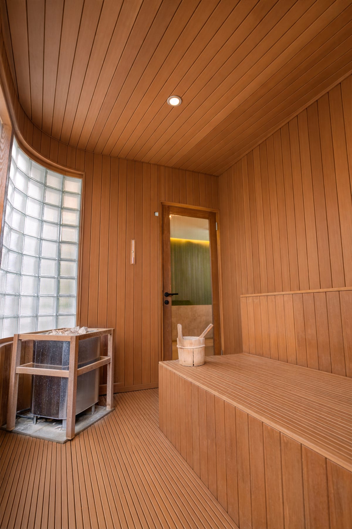 Timber sauna with a stone heater, bench and glazed door, built by Tropical Pool in Bali