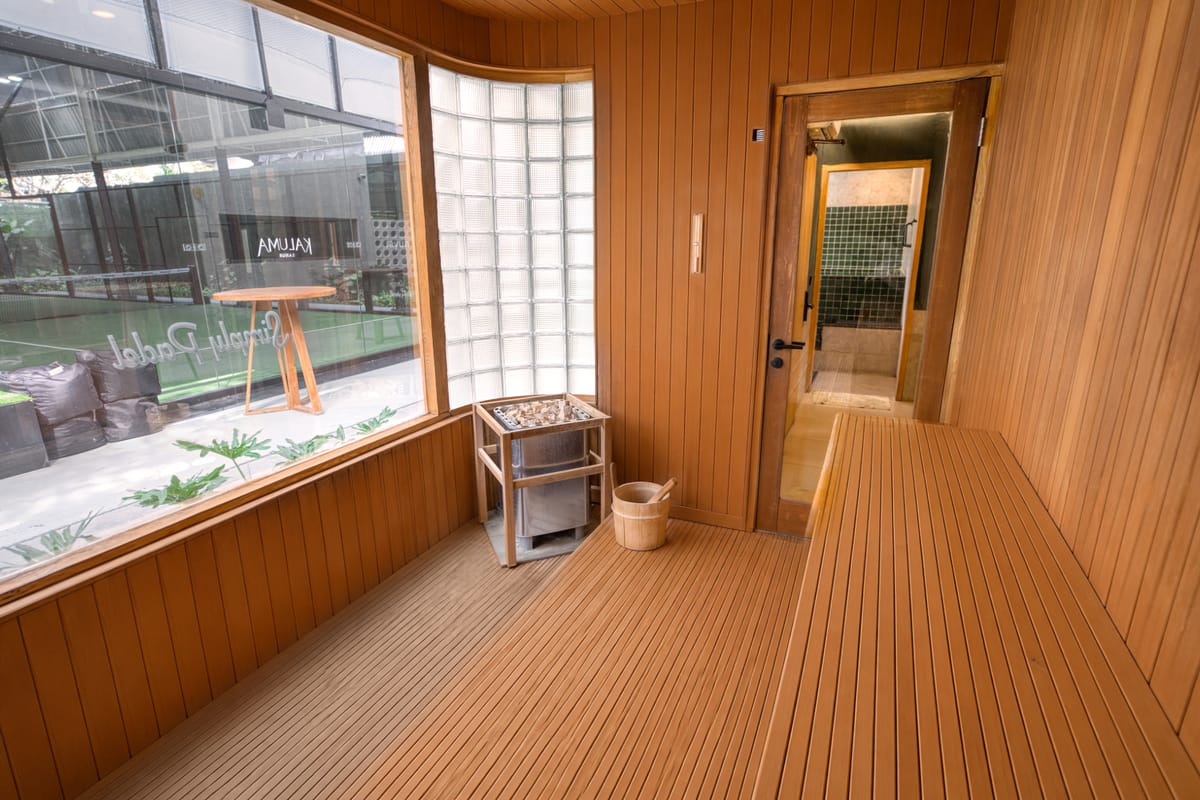 Timber-clad sauna interior with a heater and hot stones, a wooden bucket and ladle and a bench, built by Tropical Pool at a wellness club in Bali